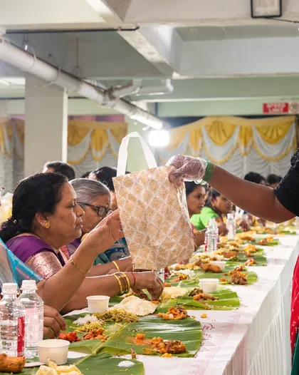 Server placing dishes on banana leaves.