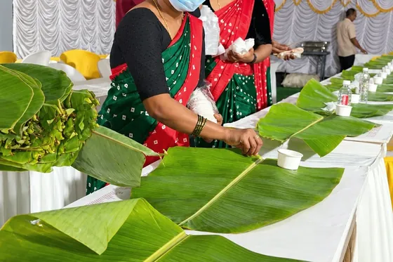 Long table set with banana leaves before guests sit.